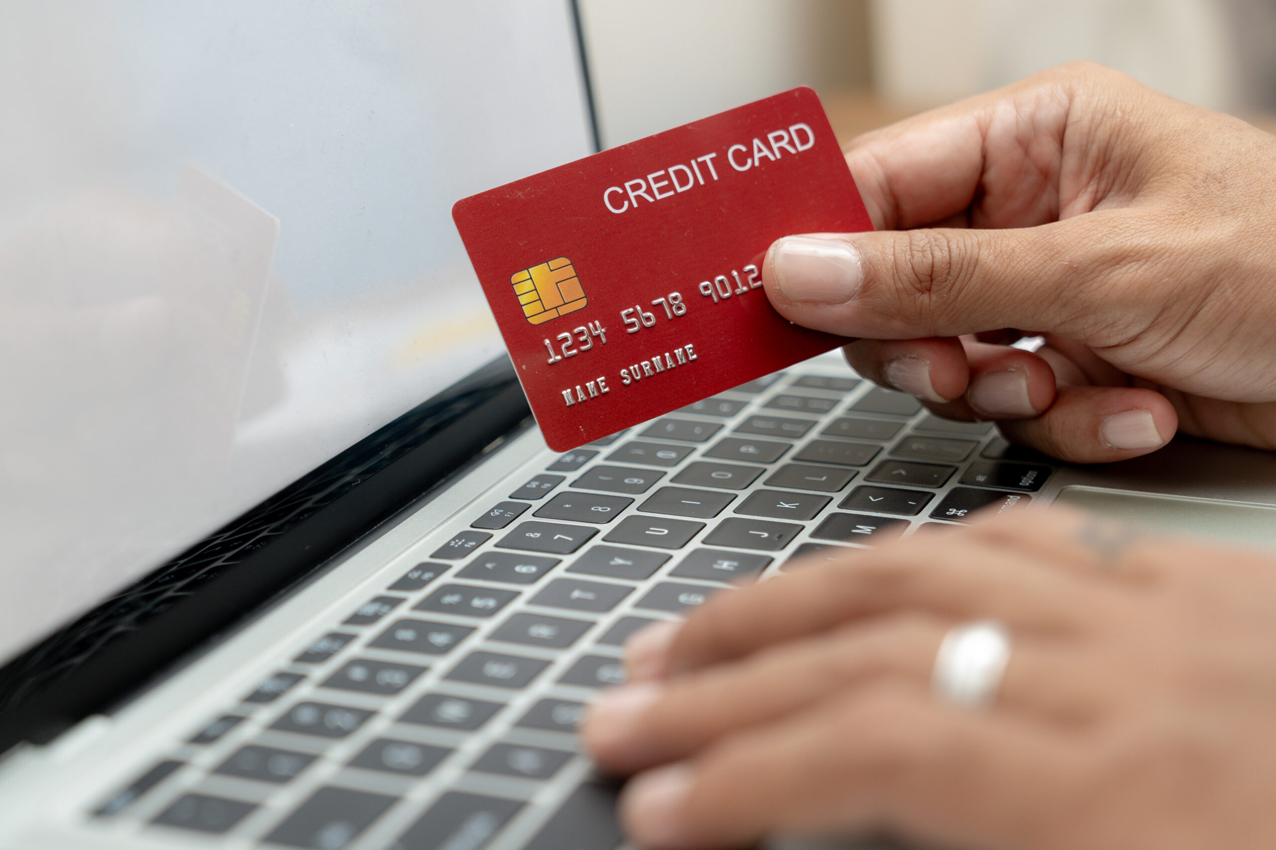 A person at a computer safely using a credit card online to avoid fraud | Braddock Law | Denver, CO